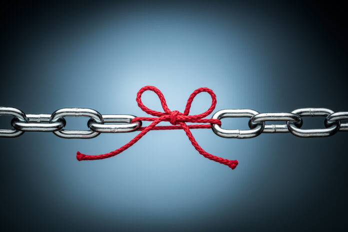 Two metal chains tied together with red string bow signifies the link between learning and strategy